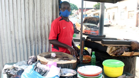 A mask-wearing man sells 'choukouya', seasoned and braised mutton and beef in Treichville, a working-class district of Abidjan, the economic capital of Côte d'Ivoire. Informal workers have been among those most affected economally by COVID-19 (Photo: Jennifer A. Patterson/ILO via Flickr, CC BY-NC-ND 2.0)